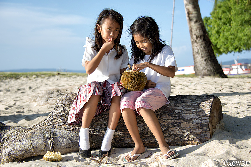Филиппинские девочки едят маранг на берегу моря.